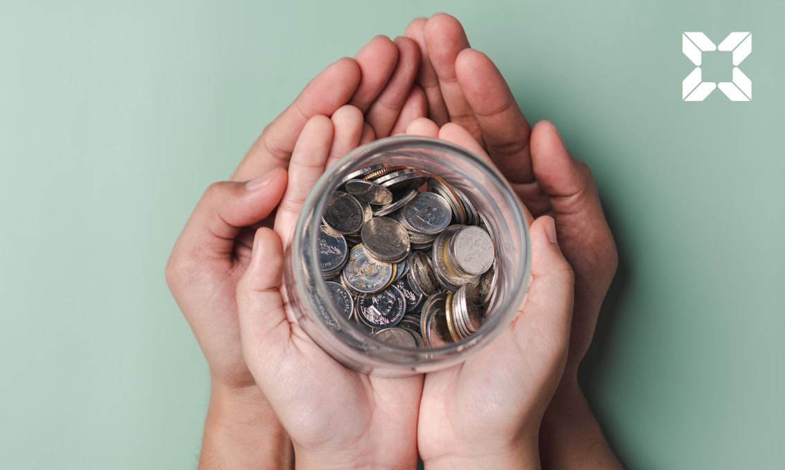 Two overlapped hands hold a jar of money