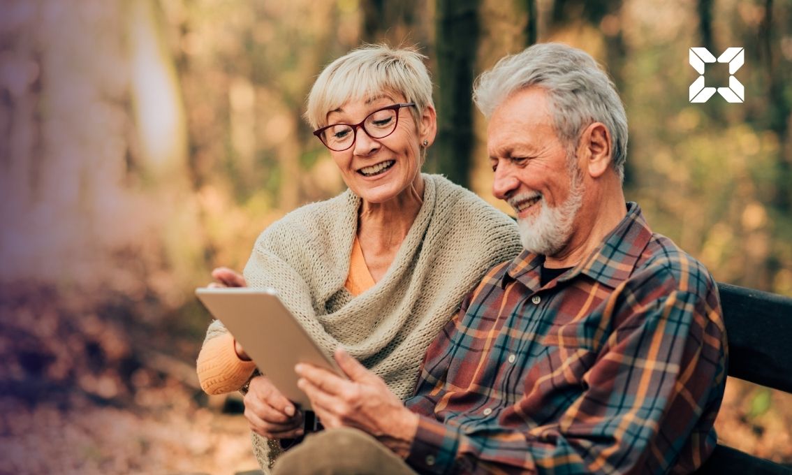 Elderly couple sit on bench reading document