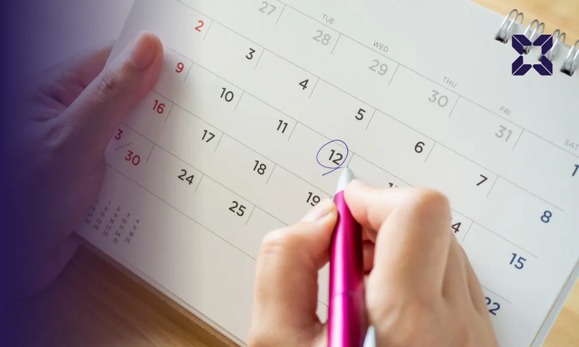 Person holding a pen circling a date on a calendar