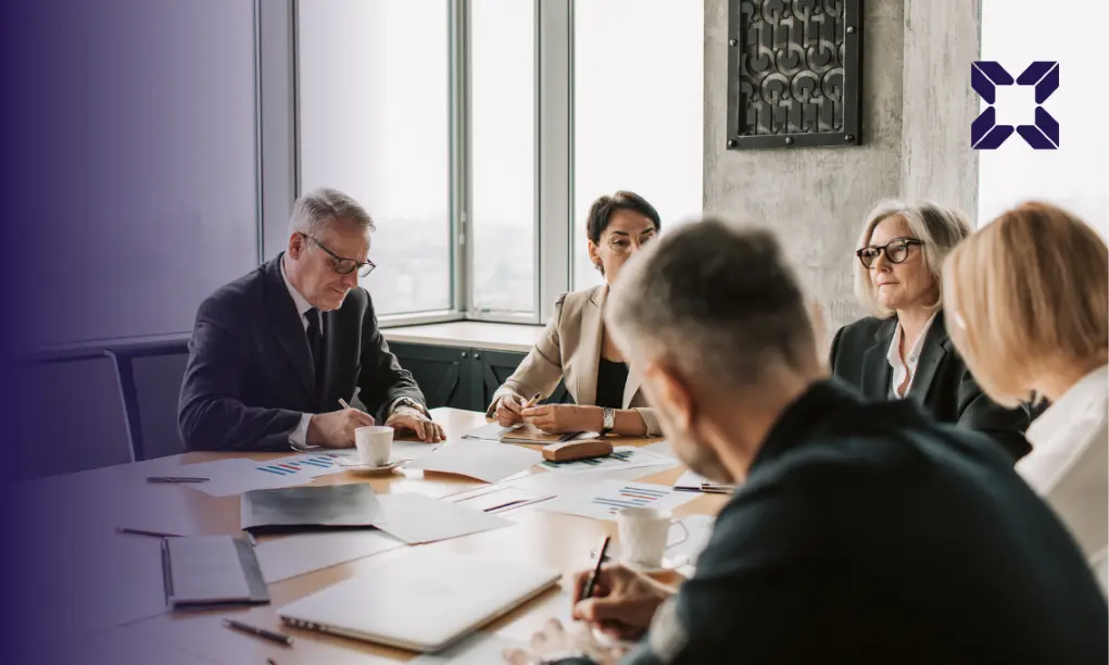 Men and women sitting around a boardroom table in a business meeting