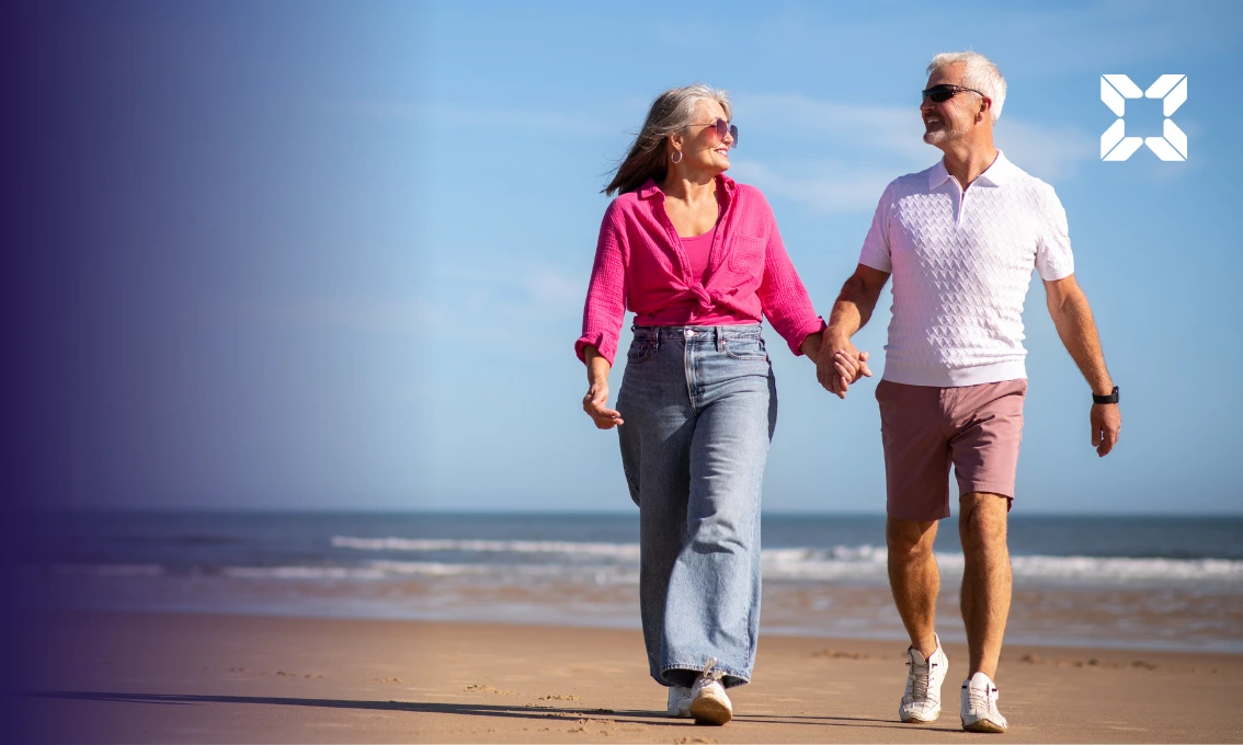 A couple walking hand in hand on a sunny beach.